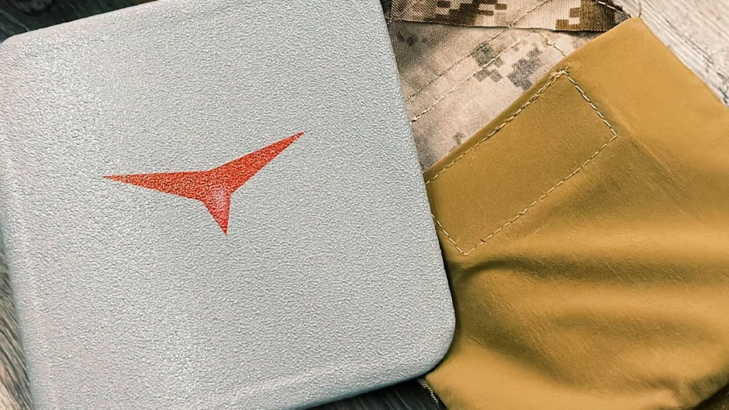 Боковая бронеплита Atlant Armour с красным логотипом бренда на фоне тактического снаряжения